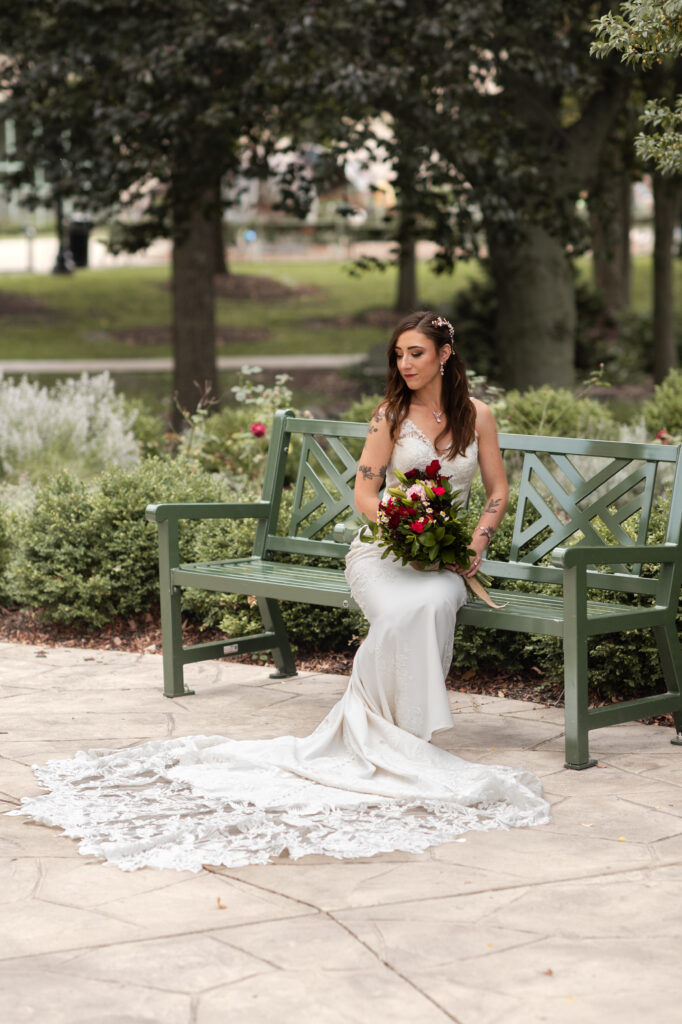 bride sitting on a bench in middle of a garden